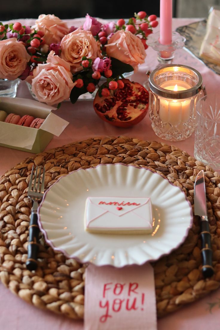 a place setting with pink flowers and candles