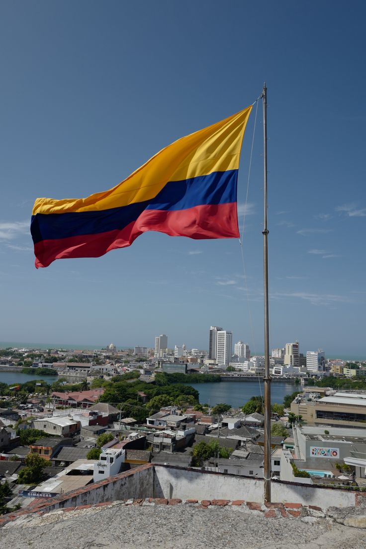 a flag flying in the wind on top of a building next to a body of water