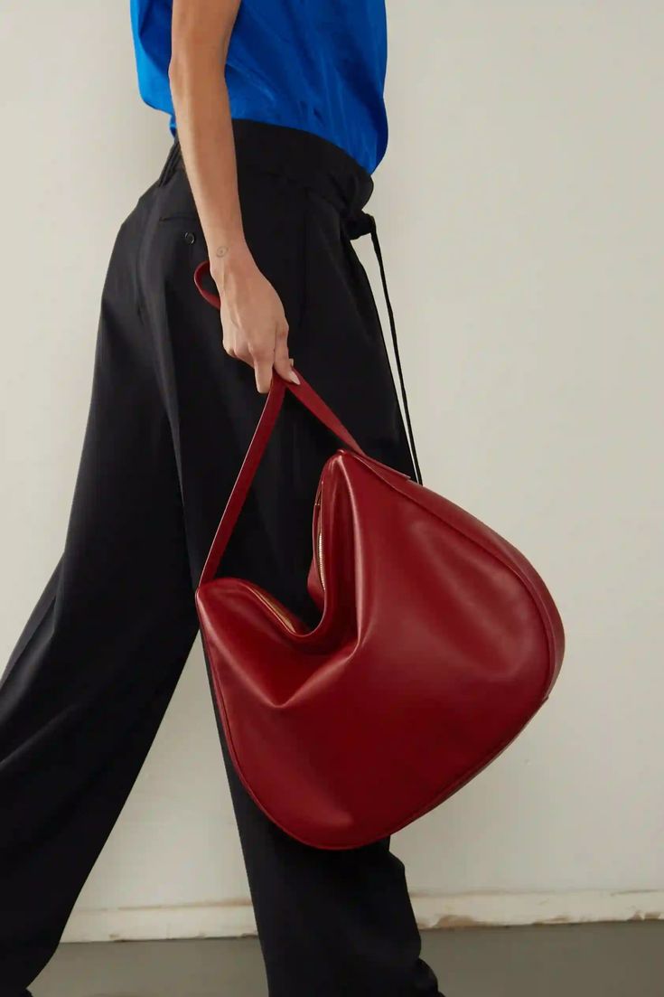 The Large Saddle in smooth red is a statement piece, with a half-moon shaped body, fine hand turned piping and uncompromised attention to detail. A versatile, large shoulder bag that combines modern elegance with practical functionality and a signature soft slouch. Ideal as a work bag, every day bag or a light travel bag. Handcrafted exclusively in our Melbourne Atelier from the finest Italian soft smooth leather. Delivered in an exclusive A-ESQUE cotton drawstring dust bag for preservation and Red Shoulder Bag With Round Handle For Daily Use, Chic Red Bags With Round Handle, Red Shoulder Bag With Round Handle For Shopping, Modern Red Shoulder Bag With Large Capacity, Modern Red Hobo Bag With Double Handle, Modern Red Hobo Bag, Modern Burgundy Shoulder Bag, Modern Red Hobo Bag With Top Handle, Modern Red Top Handle Hobo Bag