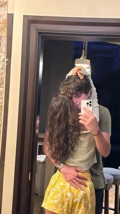 a man and woman taking a selfie in front of a mirror with their arms around each other