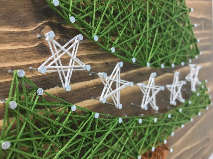 string wrapped christmas tree decorations on wood planks with green grass and white stars hanging from them