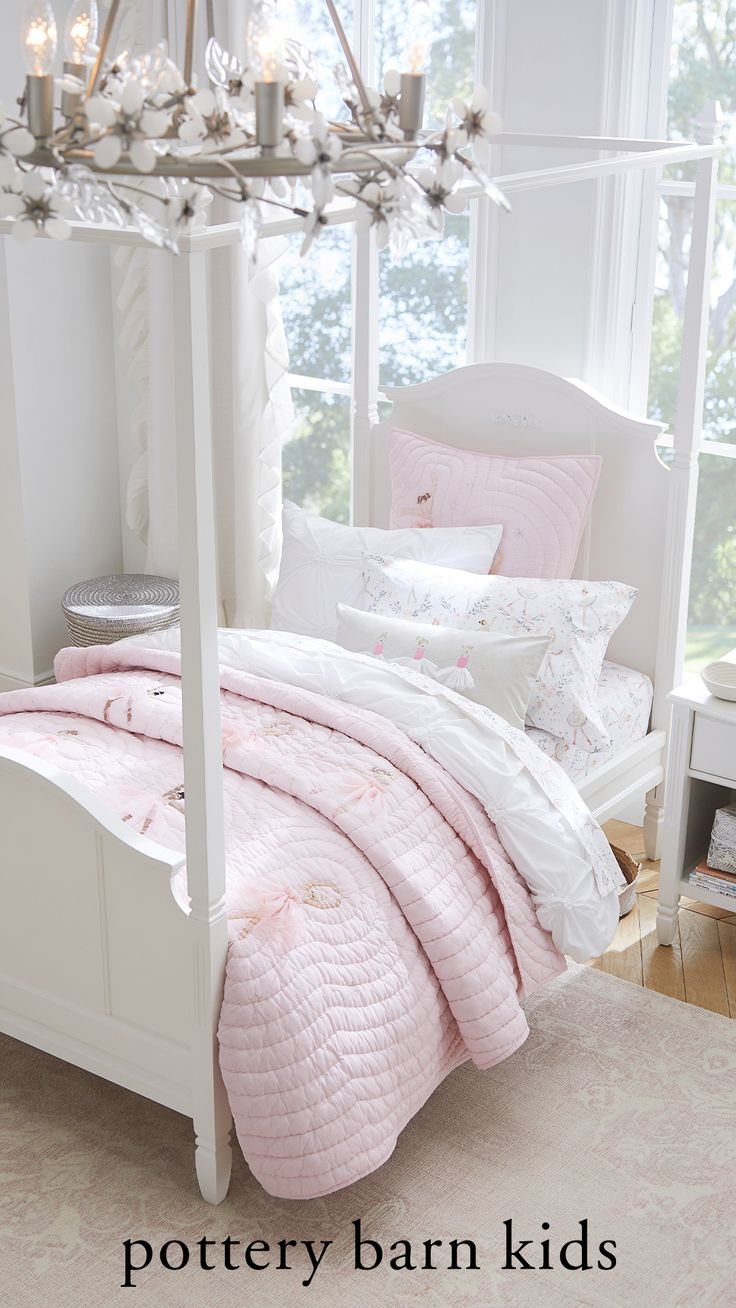 a white bed with pink comforter and pillows