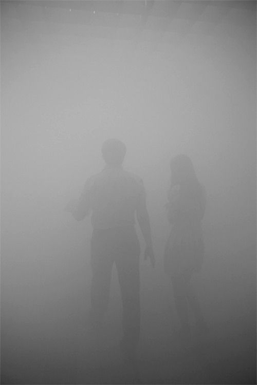 two people standing in the middle of a foggy area