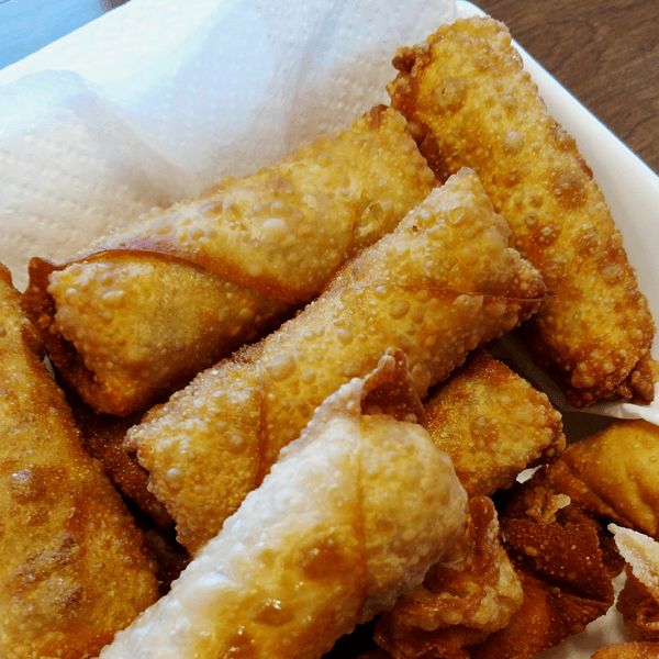 some fried food is in a white bowl on a wooden table and it looks like they are ready to be eaten