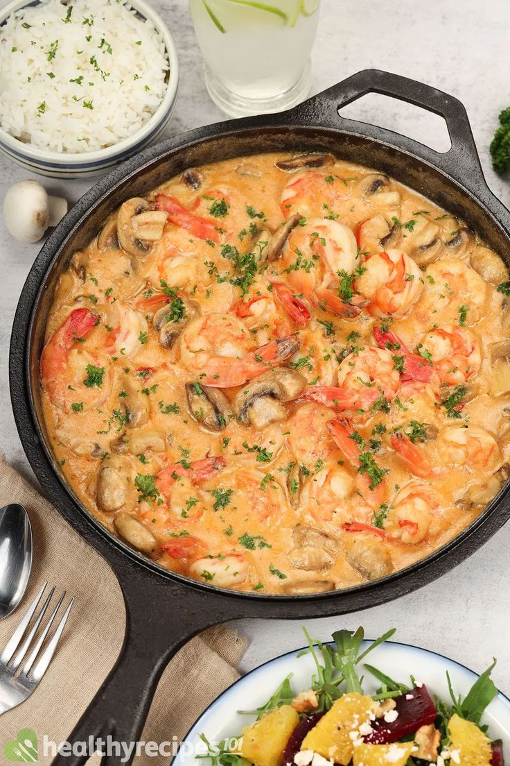 a skillet filled with shrimp and rice next to other food on the counter top