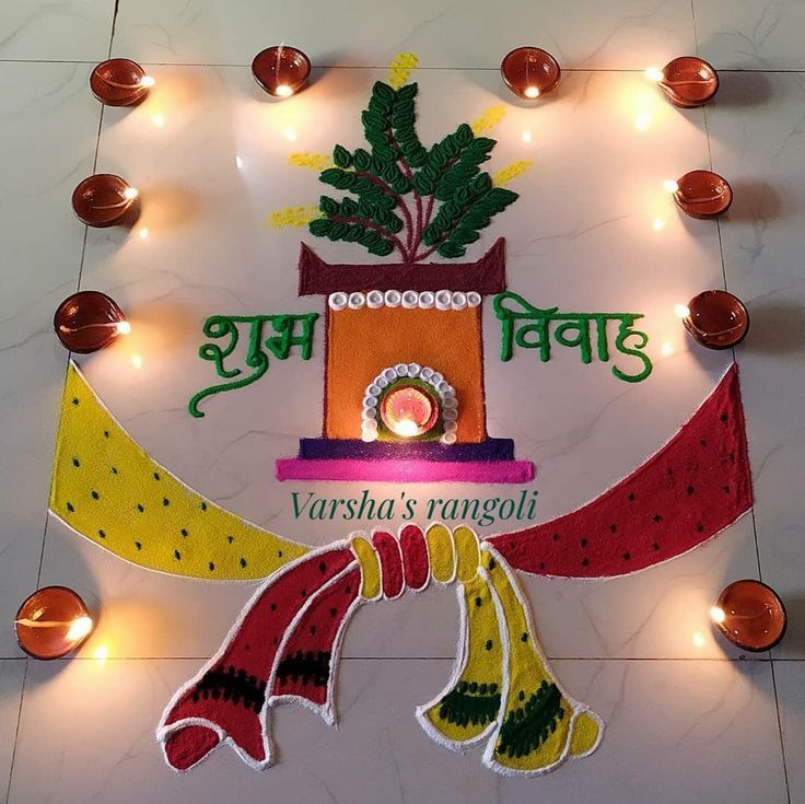 a decorated sign with lights around it and candles on the floor behind it that reads varsha's rangoli