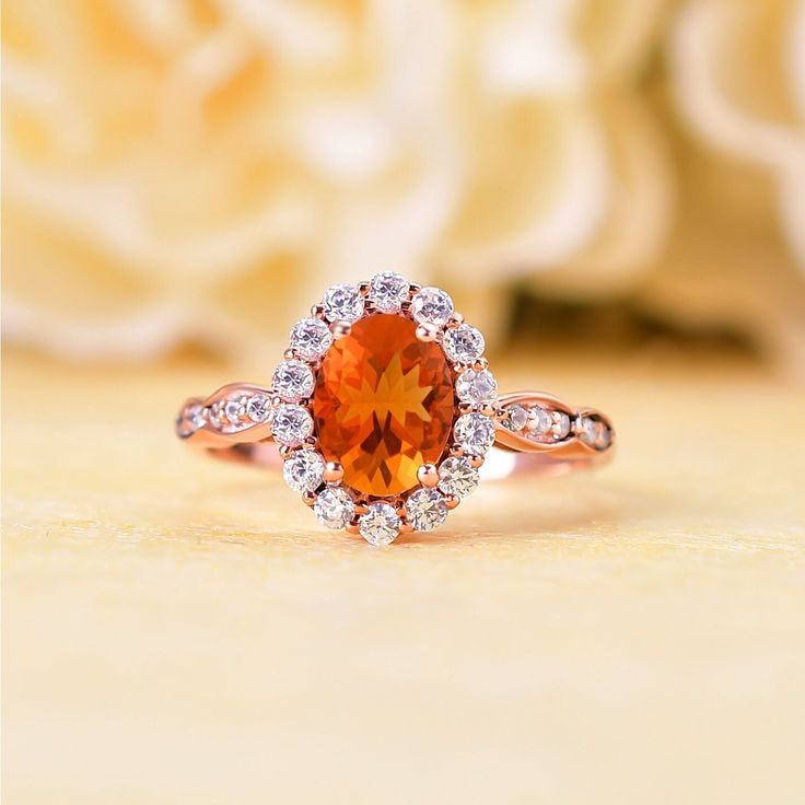 a close up of a ring with an orange stone in the center and white diamonds around it