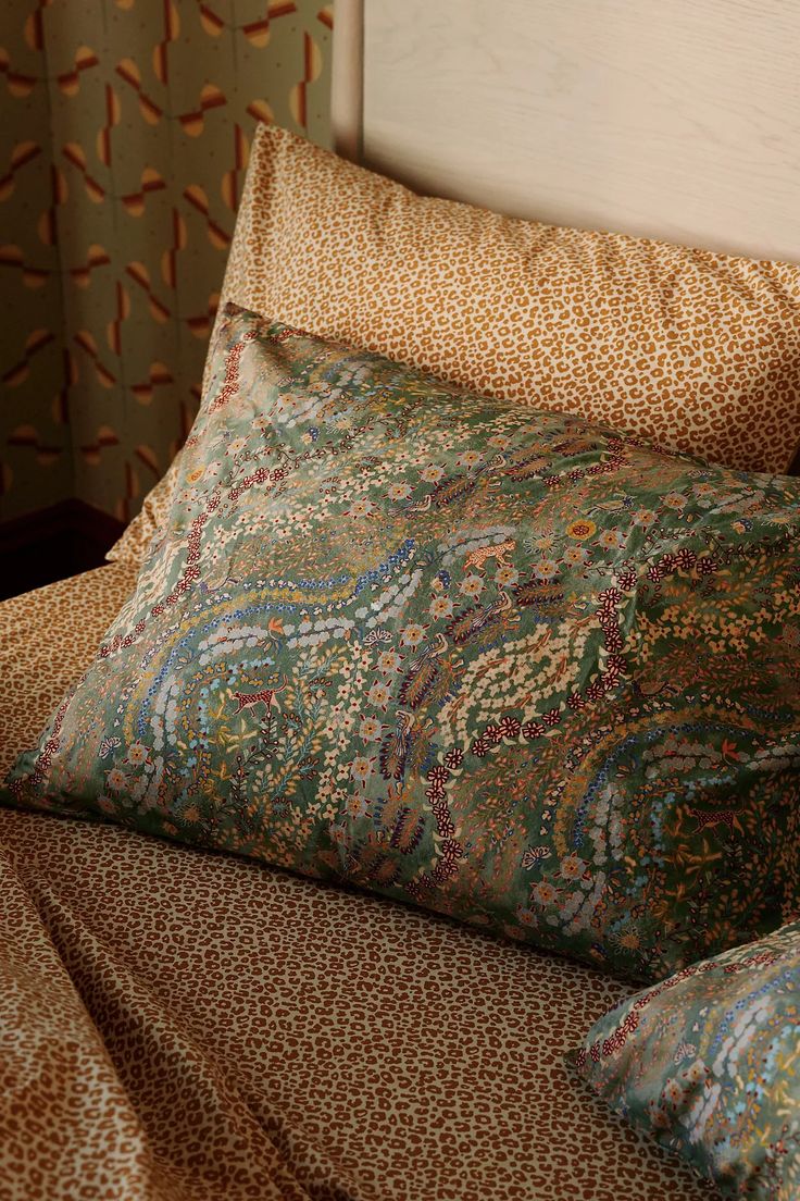 two pillows on top of a bed next to a wall with animal print sheets and curtains