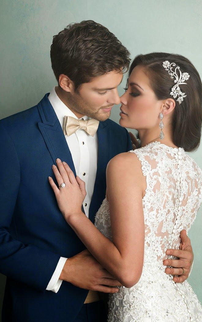 a man in a blue suit and woman in a white dress are embracing each other