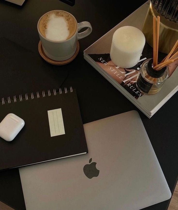 an apple laptop computer sitting on top of a desk next to a cup of coffee