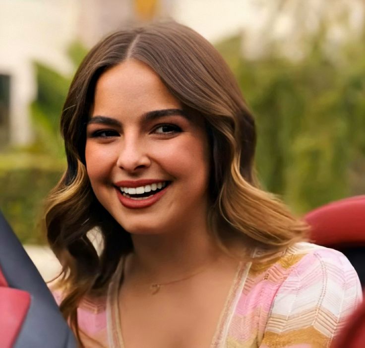 a woman sitting in a car smiling at the camera