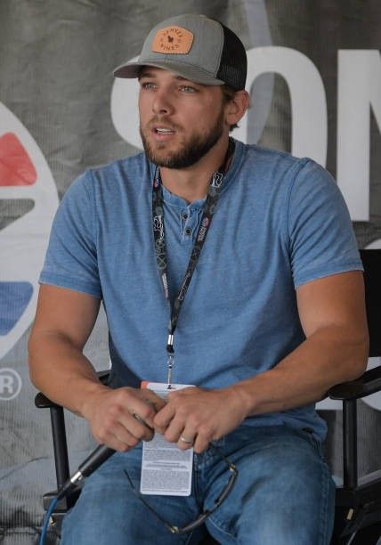 a man sitting in a chair with a baseball cap on his head and badge around his neck