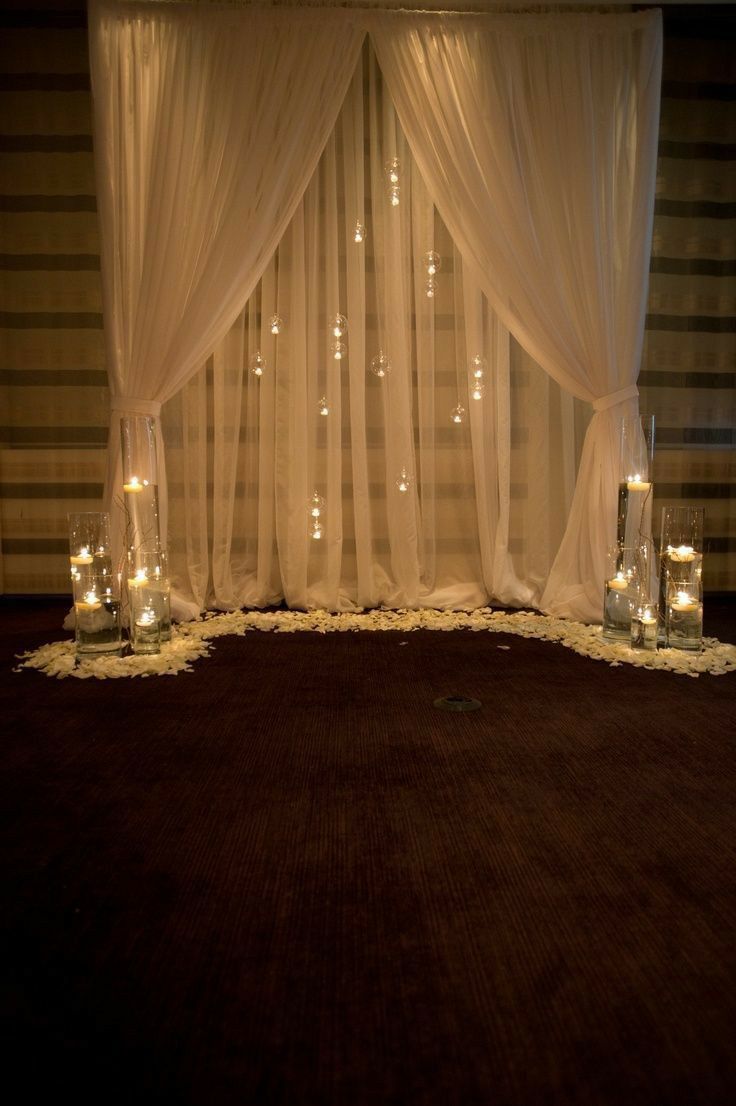 the lights are on in front of the sheered curtain and candles at the end of the bed