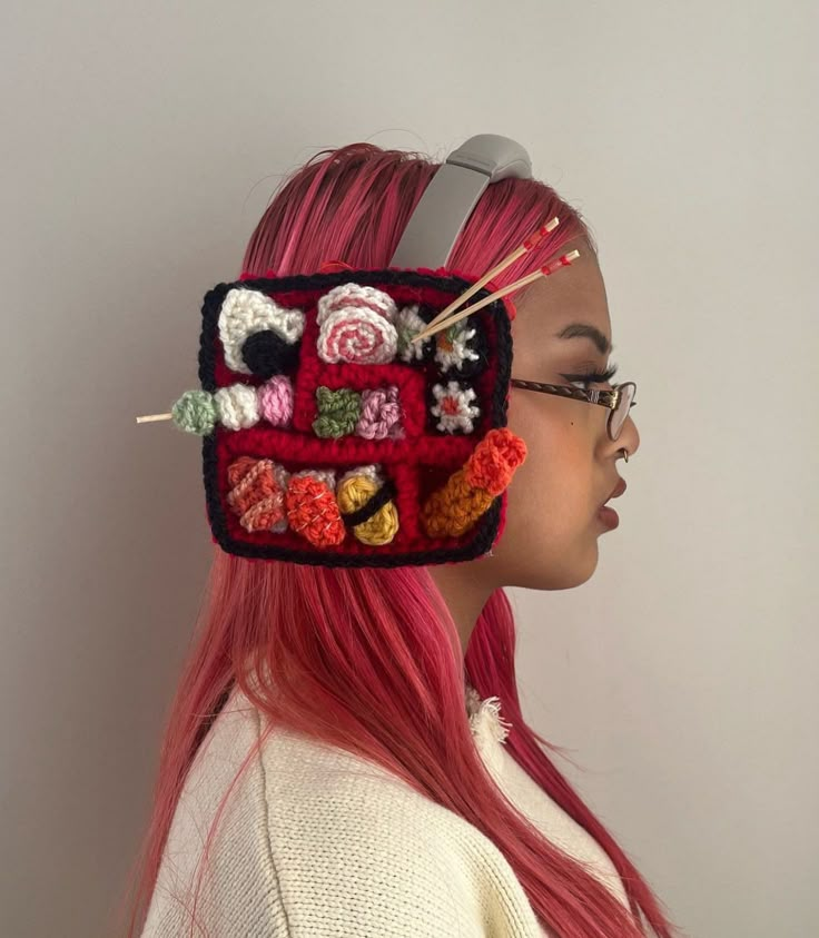 a woman with pink hair wearing a crocheted head piece