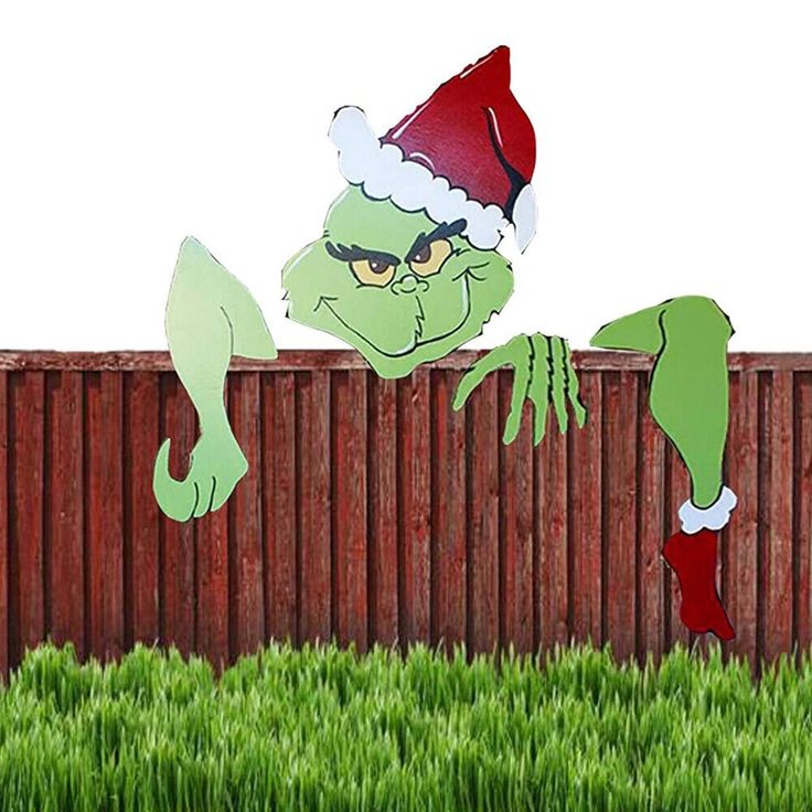 an image of a cartoon character in the grass wearing a santa hat and holding onto a fence