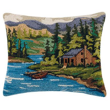 a decorative pillow with an image of a cabin on the water and mountains in the background