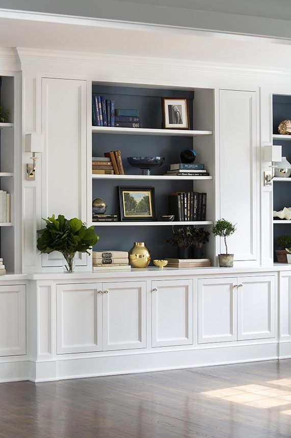 a living room filled with lots of white bookshelves next to a wooden floor