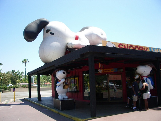 two people are standing in front of a giant snoopy dog statue on the side of a building