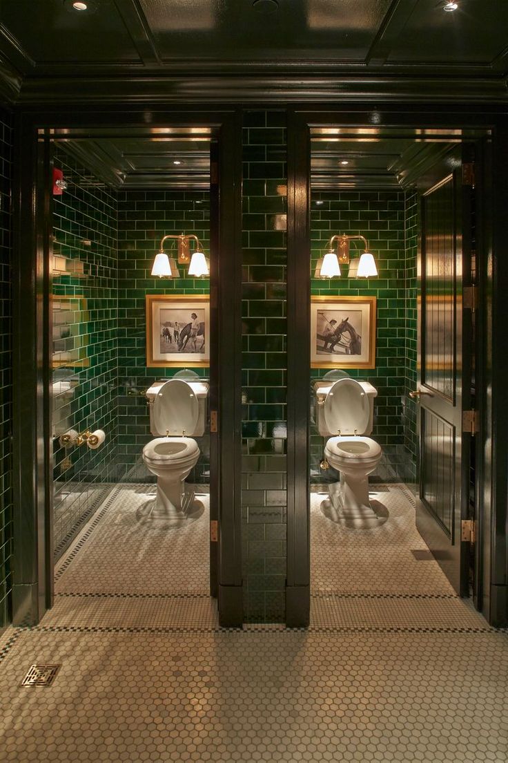 two toilets in a bathroom with green tiled walls and flooring on either side of them