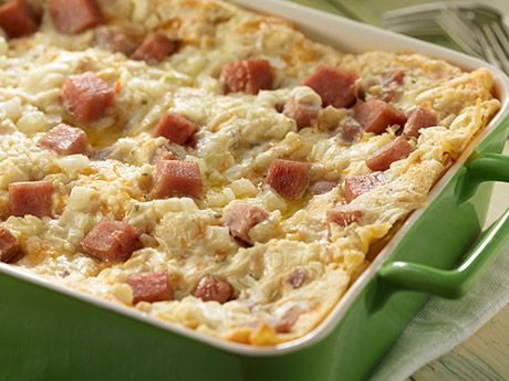 a green casserole dish with ham and cheese in it sitting on a table