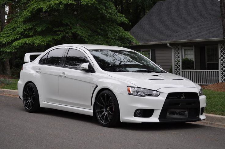 a white car is parked on the side of the road in front of a house