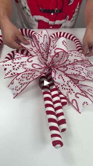 someone is making a christmas wreath out of candy canes and wrapping it in red and white