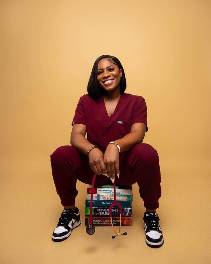 a woman sitting on the floor with some books in front of her and smiling at the camera