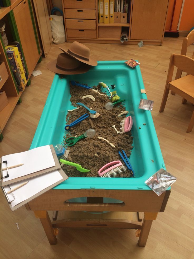 a child's play table filled with toys and dirt in the middle of a room