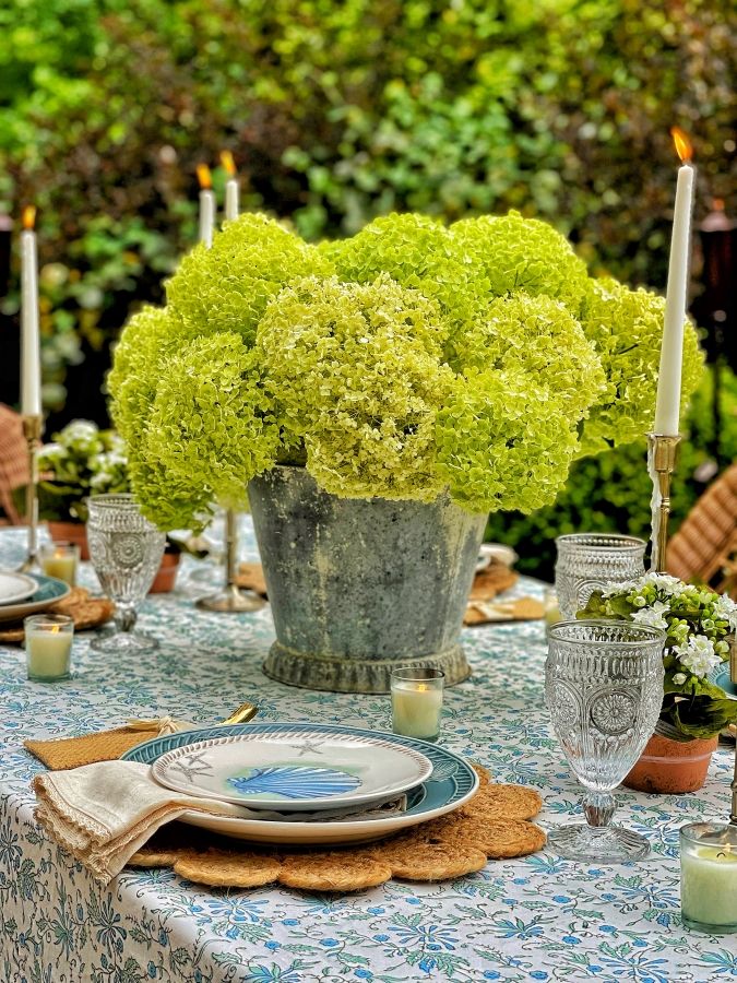 a table set with flowers and candles for an outdoor dinner