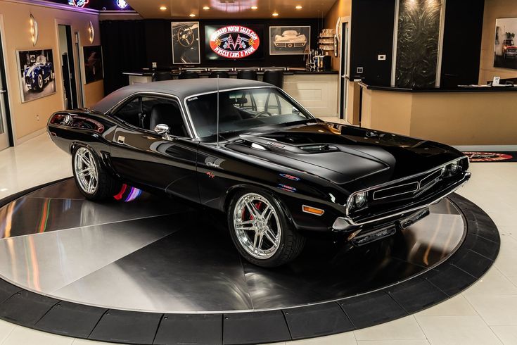 a black muscle car is on display in a showroom with other cars and memorabilia