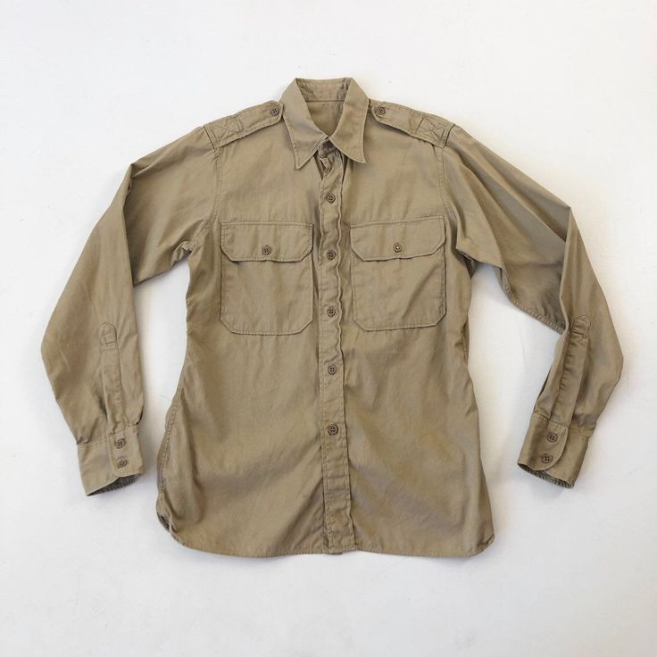 "1950's Marines khaki long sleeve shirt has a buttoned chest pockets, epaulettes, and a button front and cuff. Condition Structurally good. Has yellowish discoloration across the back, on both sleeves and around the front hem. Measurements Chest 40\" Waist 36\" Shoulder 15\" Sleeve length 25\" Length 27.5\" front, 30.5\" back. Best for a size small." Khaki Long Sleeve Shirt With Flap Pockets, Classic Khaki Shirt With Pockets, Khaki Button-up Shirt With Button Cuffs, Classic Long Sleeve Khaki Shirt, Khaki Military Collared Shirt, Classic Khaki Shirt With Button Cuffs, Khaki Collared Military Shirt, Classic Khaki Shirt With Buttons, Khaki Shirt With Spread Collar And Buttons