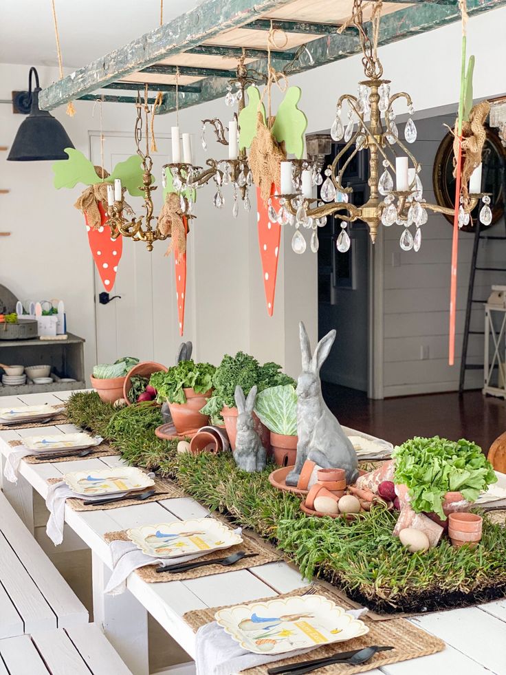 a long table topped with lots of green plants and bunnies hanging from the ceiling