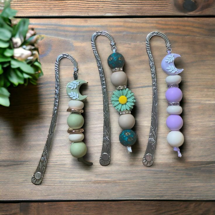 four different bracelets with flowers on them sitting on top of a wooden table next to a potted plant