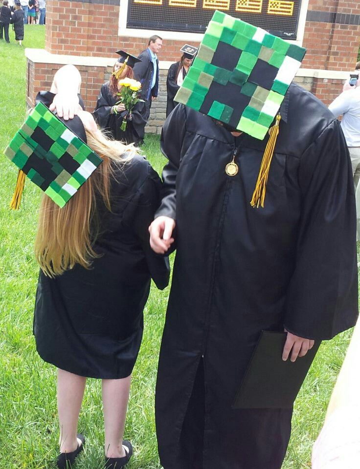 two people wearing graduation caps and gowns in the grass