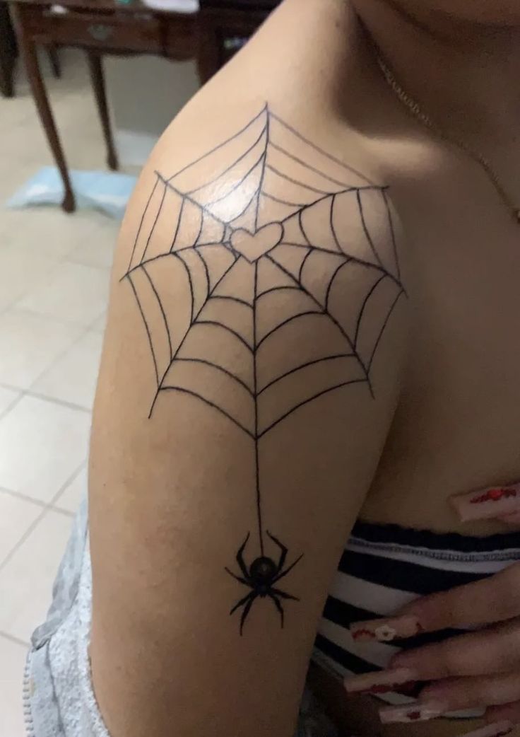 a woman's arm with a spider web tattoo on the back of her shoulder