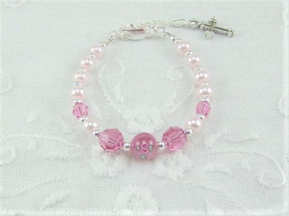 "Tiny pale pink pearls, rose Swarovski crystals and a dark pink rose lampwork bead are strung into a darling infant girl bracelet. A silver plated extension chain makes this tiny bracelet adjustable from 4 1/2\" to 5 3/4\" in length. The central bead is a dark pink Czech glass lampwork rose bead. The 4mm pale pink pearls are complimented with 4mm round rose Swarovski crystals. The 6mm Rose designed lampwork bead, along with the 6mm rose crystals are spaced with tiny silver spacer beads. A silver Pink Round Rosary Bracelet Gift, Pink Beaded Bracelets With 8mm Beads For Birthday, Personalized Pink Pearl Bracelet For Birthday, Personalized Pink Pearl Bracelet With Round Beads, Adjustable Pink Rosary Bracelet With 8mm Beads, Pink 8mm Beads Jewelry For Wedding, Pink Pearl Beaded Bracelet For Birthday, Pink Pearl Bracelet For Birthday, Elegant Pink Bracelets For First Communion