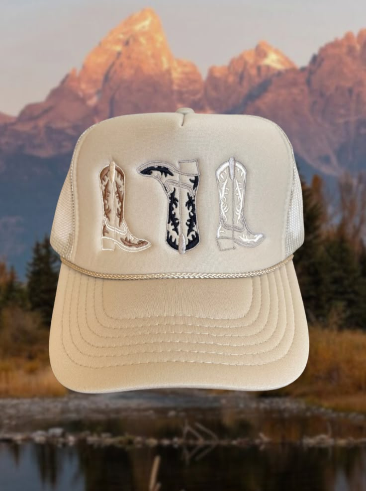 Tan trucker hat with 3 embroidered cowboy boots in the perfect neural fall colors One size fits most due to adjustable snap closure. Breathable mesh back. Trucker Hats Western, Mackenzie Aesthetic, Western Fall Outfits, Embroidered Cowboy Boots, Hat Burning, Hats Western, Job Clothes, Western Cowgirls, Cowgirl Hats