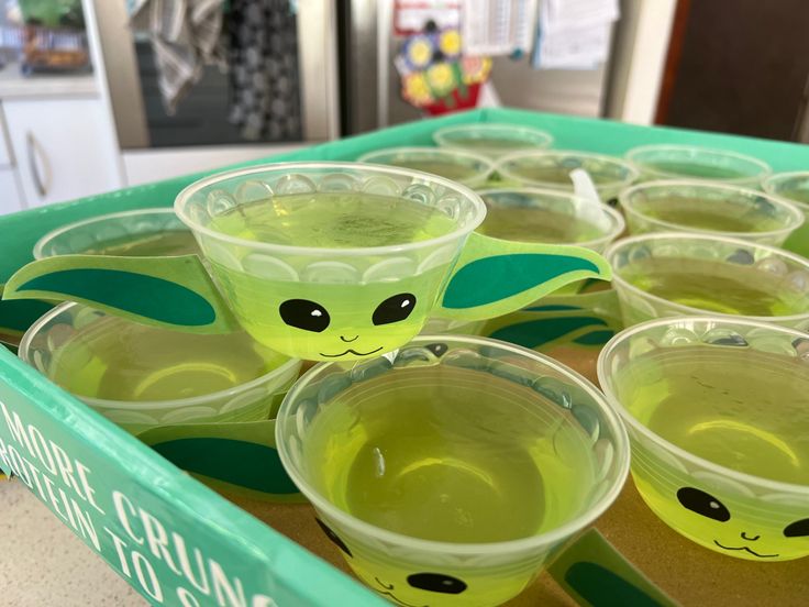 there are many cups with green liquid in the shape of baby yoda's head