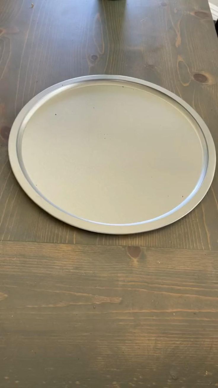 a white plate sitting on top of a wooden table next to a vase with flowers