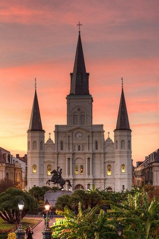 a large white building with two towers and a clock on it's side at sunset