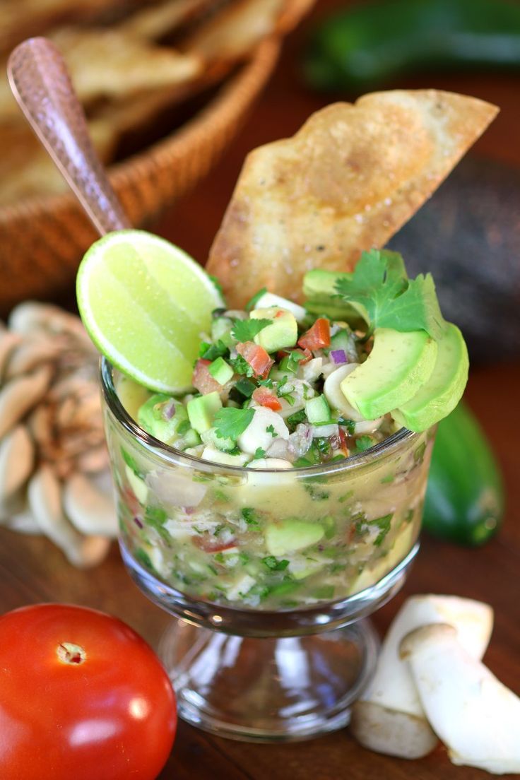 a glass bowl filled with guacamole, salsa and tortilla chips