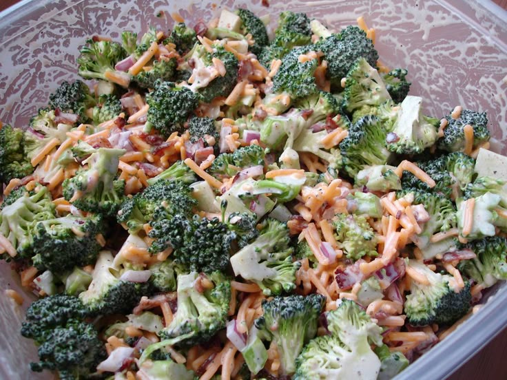 a plastic container filled with broccoli and other food on top of a table