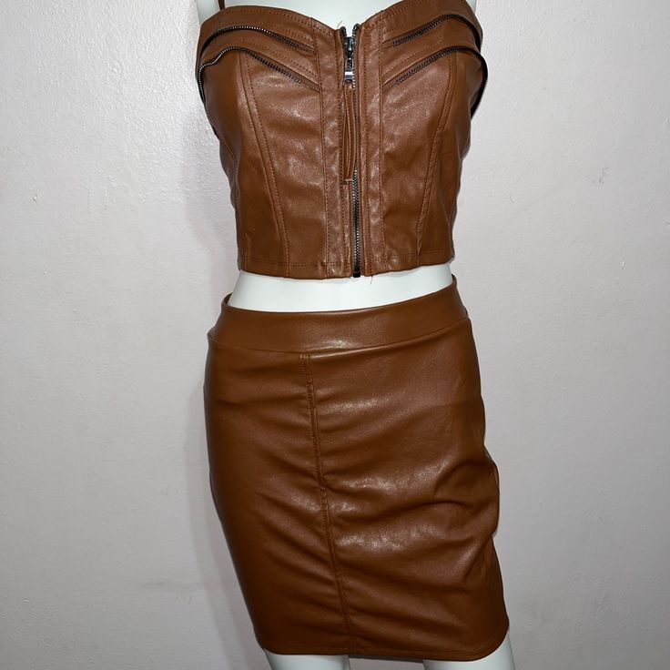 a mannequin wearing a brown leather skirt and cropped top with zippers