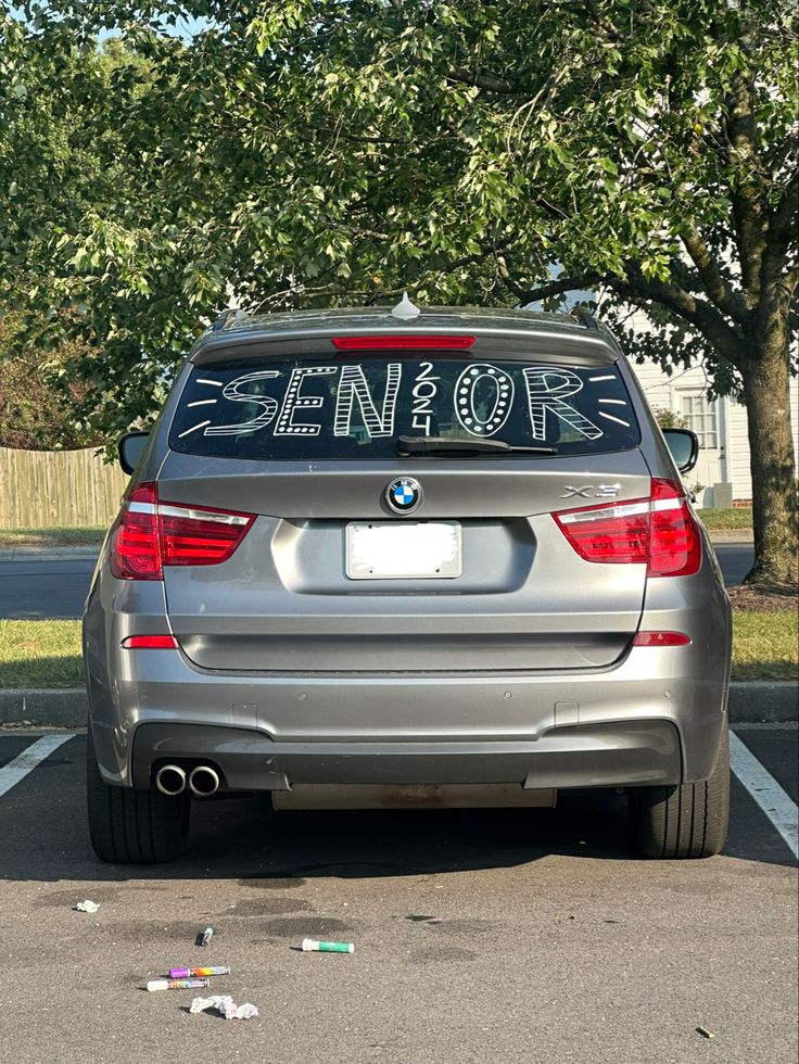 a silver car parked in a parking lot with the word senior on it's back window