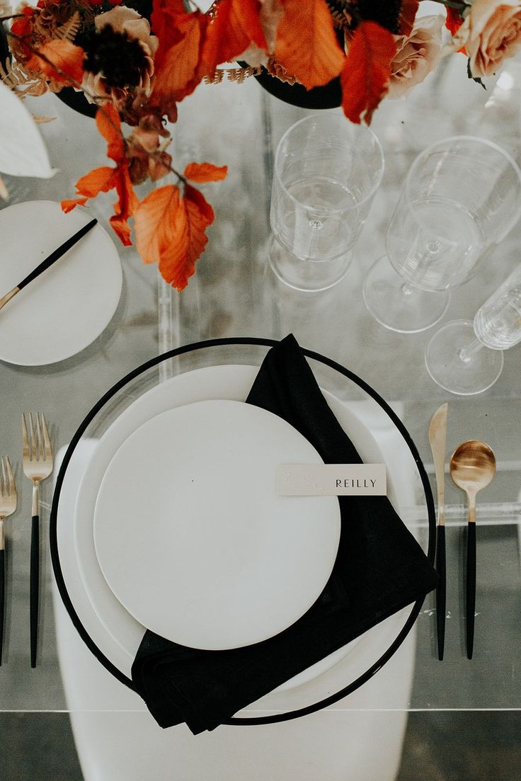 the table is set with black and white place settings, silverware, and flowers