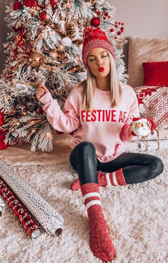 a woman sitting on the floor in front of a christmas tree wearing red and white socks