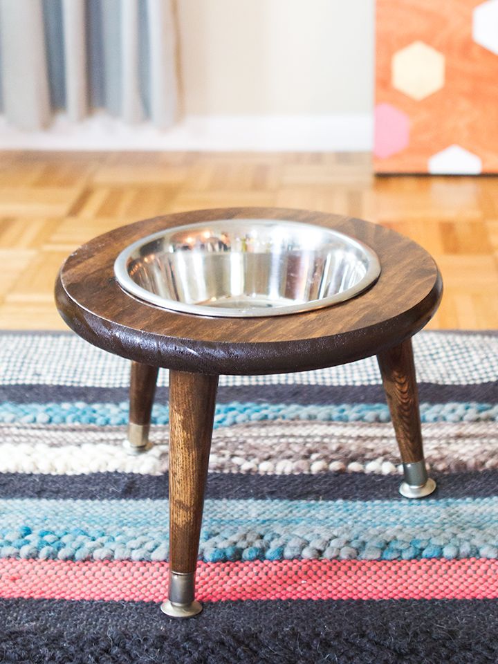 a wooden table with a metal bowl on it and a rug in front of it