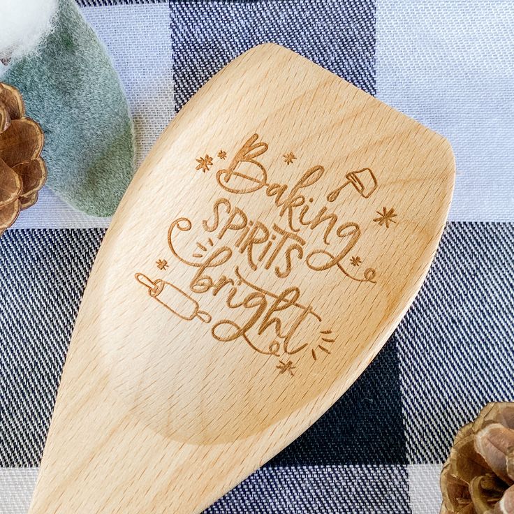 a wooden spoon sitting on top of a checkered table cloth next to pine cones