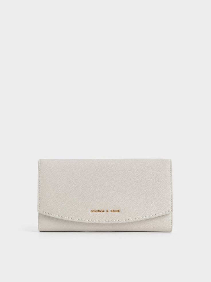 Oozing ultimate chic vibes with the light grey hue, this long wallet demonstrates just how fashion meets functionality. Boasting a modern curved front flap, this gem secures shut with a snap-button closure, keeping all your items safe and within reach. Carry it as a mini clutch with a woven tunic dress and stiletto heels for a casual weekend look. Complete your ensemble with a pair of butterfly sunglasses to ace your fashion game. Luxury Modern Rectangular Wallets, Luxury White Wallets For Formal Occasion, Handmade White Wallets, Luxury Modern Formal Wallets, Chic Wallets With Magnetic Closure For Everyday Use, Chic Everyday Wallet With Magnetic Closure, Chic Everyday Wallets With Magnetic Closure, Modern Trifold Wallet For Evening, Elegant Gray Wallets For Formal Occasions