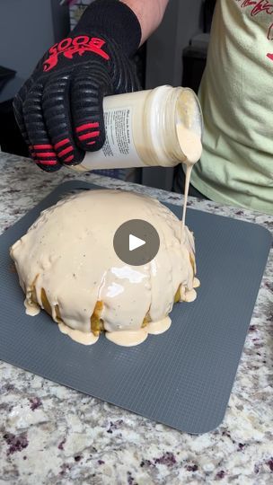 someone pouring icing onto a cake on top of a counter